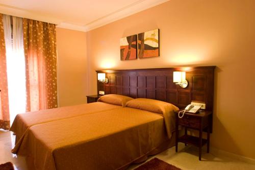 Un dormitorio con una cama y un teléfono en una mesa. en Hotel Sierra Hidalga, en Ronda