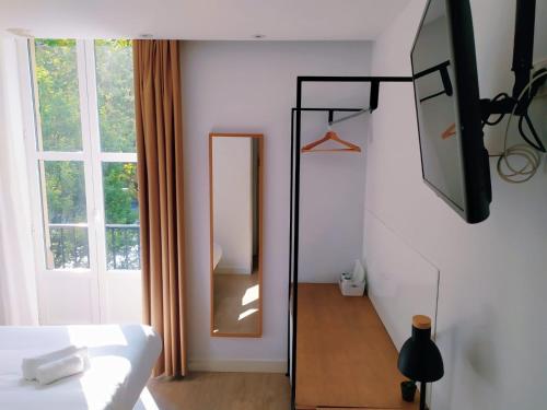 a bedroom with a bed and a mirror and a window at Pensión Sarriegi in Donostia-San Sebastián