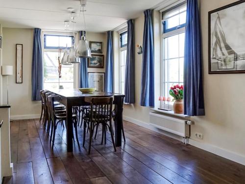 a dining room with a table and chairs and blue curtains at Holiday Home Stavoren by Interhome in Stavoren