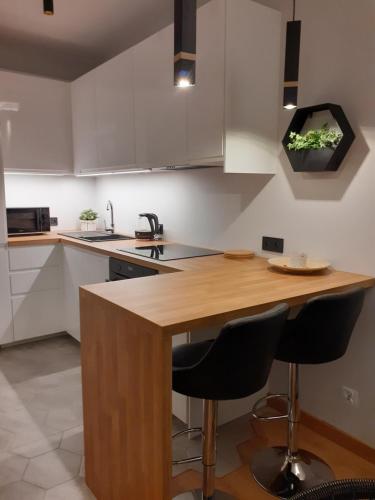 a kitchen with a wooden island with two bar stools at APARTAMENT DĄBSKA 24 TAURON ARENA in Krakow