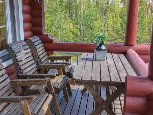 2 chaises et une table en bois sur une terrasse couverte dans l'établissement Holiday Home Harjurinne by Interhome, à Kinnula