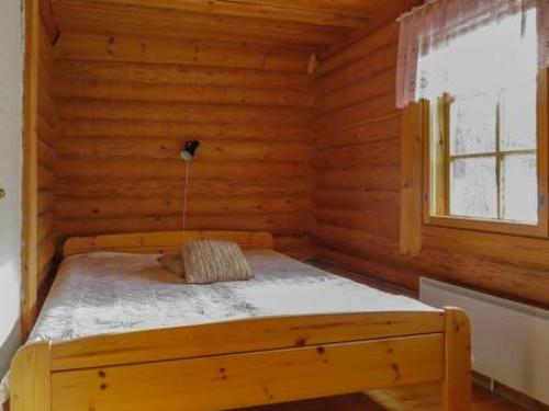 a bed in a log cabin with a window at Holiday Home Kulpakko 1 by Interhome in Tiainen