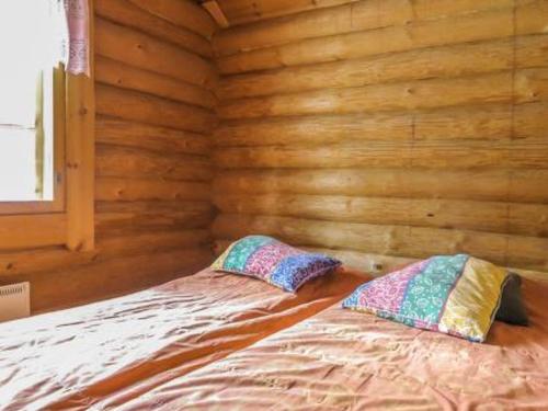 a bed in a wooden room with two pillows on it at Holiday Home Kulpakko 1 by Interhome in Tiainen