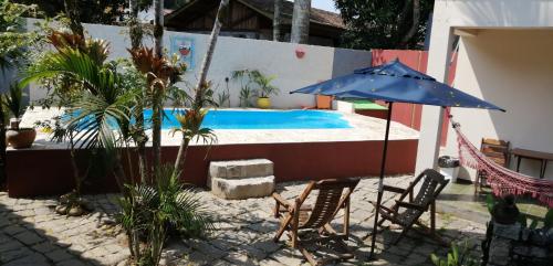 a blue umbrella and chairs next to a swimming pool at Pousada Bela Paraty in Paraty