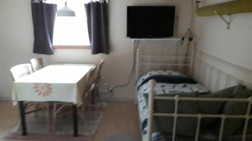 um quarto com uma cama, uma mesa e uma televisão em Granviks Bed & Breakfast em Björklinge