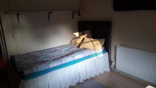 um pequeno quarto com uma cama com lençóis brancos e almofadas em Granviks Bed & Breakfast em Björklinge