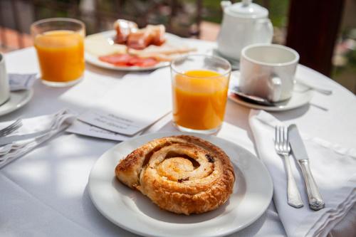 a plate with a pastry on a table with orange juice at Hotel El Convento in Arcos de la Frontera