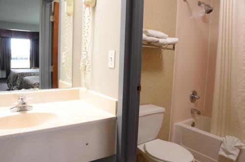 a bathroom with a sink and a toilet and a mirror at Gateway Inn in Clarksville