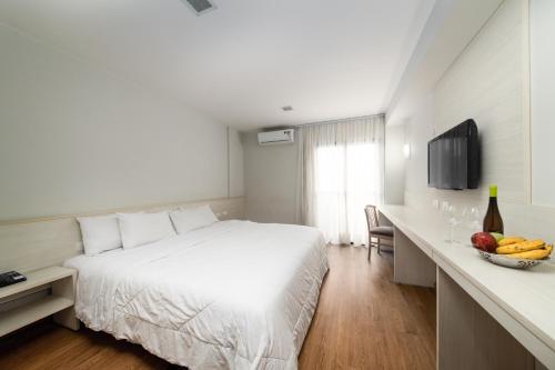 a hotel room with a bed and a table with a bowl of fruit at Rede Andrade Vernon in Curitiba