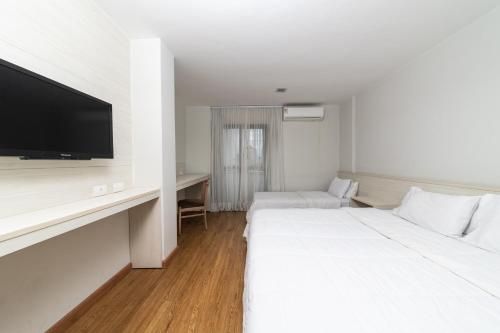 a hotel room with two beds and a flat screen tv at Rede Andrade Vernon in Curitiba