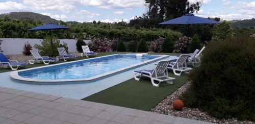 a swimming pool with lounge chairs and umbrellas at As Casinhas dos avós by Quinta do Paço in Amarante