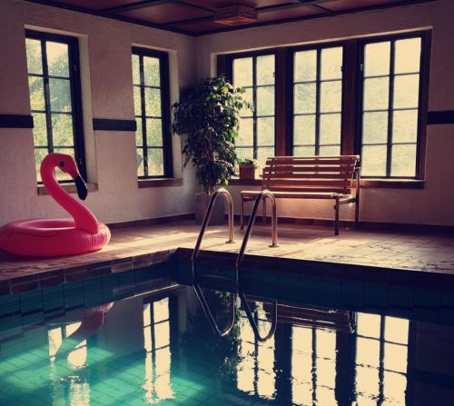 a swimming pool with a red swan and a bench at Bergakungen Stugby in Osby