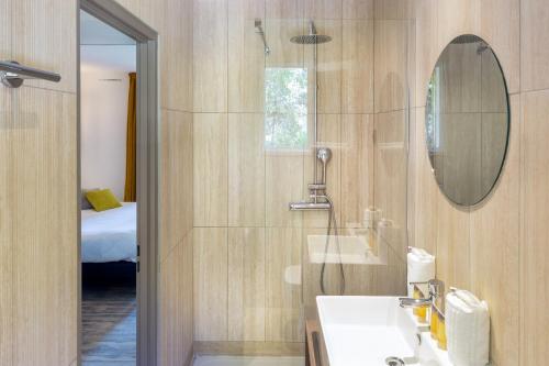 ein Bad mit einem Waschbecken und einem Spiegel in der Unterkunft SOWELL HOTELS L'Olivier in Arles