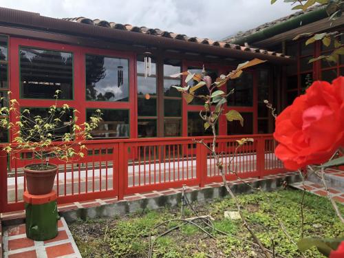 a red house with a red fence and a red rose at Ecohotel Pinohermoso Reserva Natural in Salento