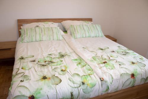 uma cama com uma colcha branca com flores em Ernas Ferienhaus em Aschbach bei Fürstenfeld