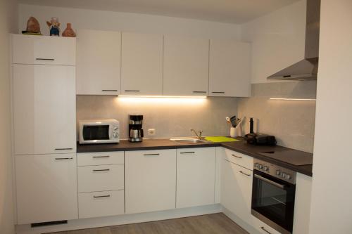a white kitchen with white cabinets and a microwave at Ernas Ferienhaus in Aschbach bei Fürstenfeld