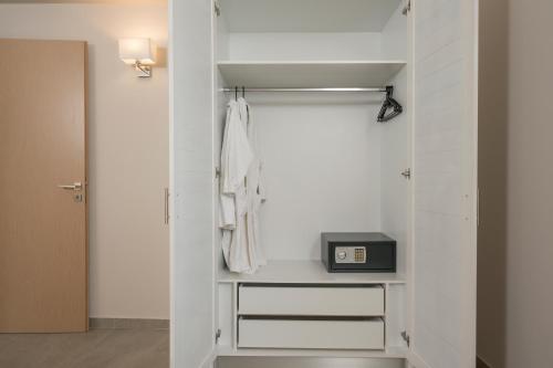 a bathroom with a white closet with a clock at Spilia Village Hotel & Villas in Spiliá