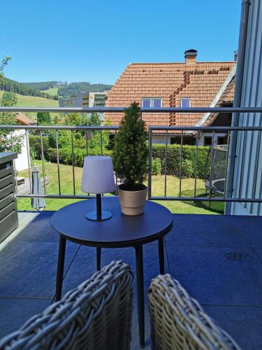 a table with a lamp and a potted tree on a balcony at MINAROSO appartements am badeparadies in Titisee-Neustadt