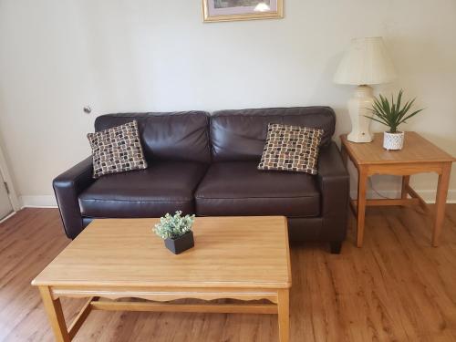 Sala de estar con sofá de cuero negro y mesa de centro en Affordable Suites Graham, en Graham
