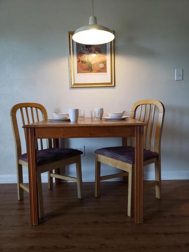 Affordable Suites Graham في Graham: طاولة خشبية مع كرسيين وطاولة ومصباح