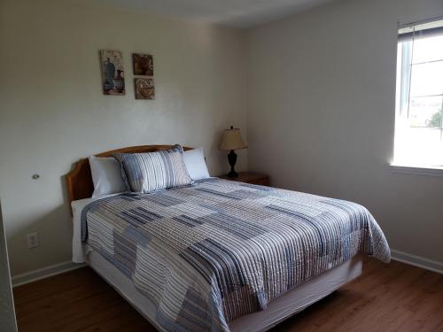 Affordable Suites Graham في Graham: غرفة نوم بسرير مع لحاف مخطط ونافذة