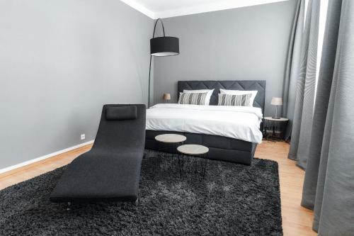 a bedroom with a bed and a black chair at Stylisches Münster City-Apartment 83 m² in Münster