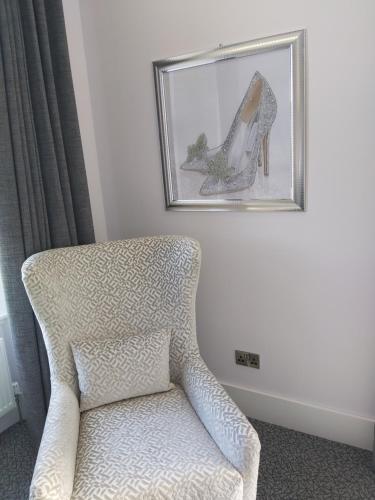 a picture of a high heel shoe on a wall next to a chair at Dean Park Hotel in Kirkcaldy