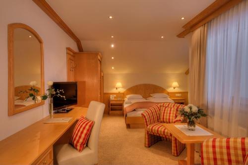 a hotel room with a bedroom with a bed and a desk at Hotel Palin in Ischgl
