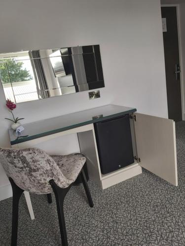 a desk with a mirror and a chair and a tv at Dean Park Hotel in Kirkcaldy