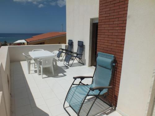 Un patio con sillas y una mesa en un balcón. en Villa Isolde, en Triscina
