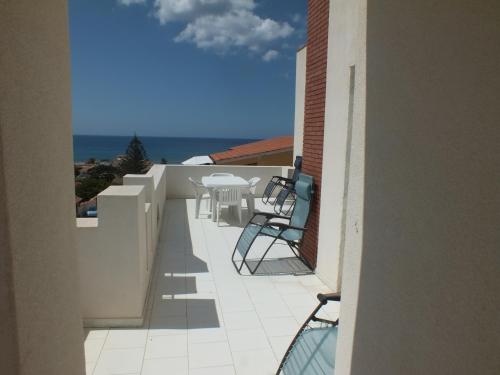 Un balcón con sillas, una mesa y el océano en Villa Isolde, en Triscina