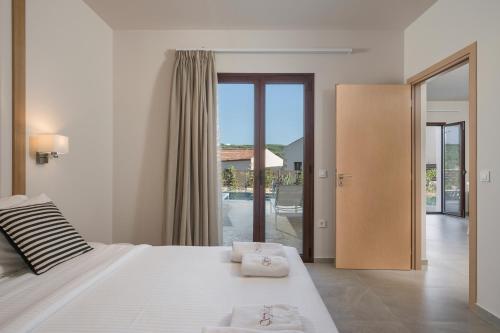 a bedroom with a large white bed and sliding glass doors at Spilia Village Hotel & Villas in Spiliá