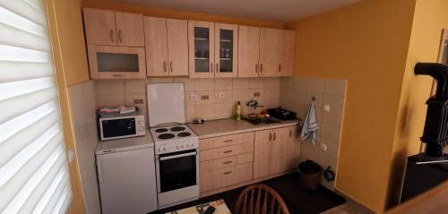 a small kitchen with white appliances and wooden cabinets at Vikendica Pored Drine in Crvica