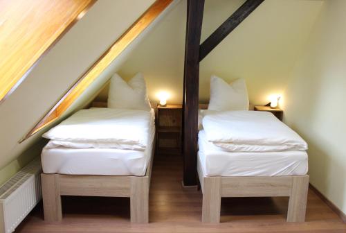 Cette chambre mansardée comprend 2 lits jumeaux et des draps blancs. dans l'établissement Villa 1895, à Leipzig