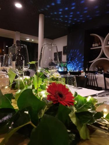 a table with wine glasses and a red flower on it at Hotel AL Mulino in Maasmechelen