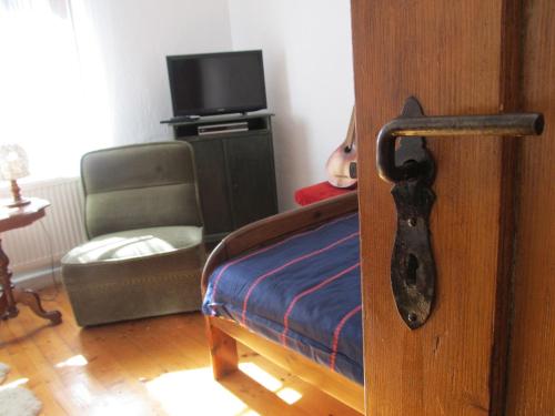 a doorhandle to a room with a bed and a chair at Chata za Górami in Zagórze Śląskie