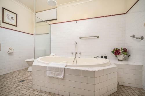 a white bathroom with a tub and a toilet at Cotswold Gardens in Armidale