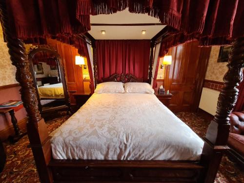 a bedroom with a four poster bed with red curtains at Bluebell House in Inverness