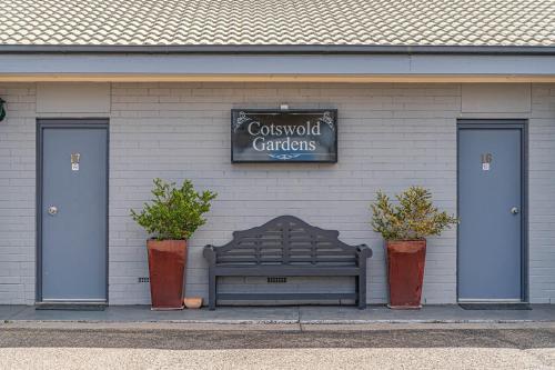 a bench in front of a building with two doors at Cotswold Gardens in Armidale
