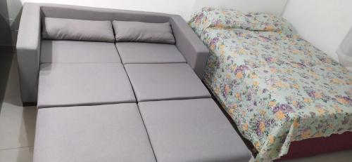 Una cama con un marco de cama gris con una colcha floral. en WB Apto condomínio Jubiabá, en Olivença