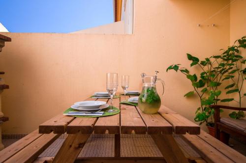 a wooden table with plates and glasses on it at Villa 6pax baby friendly Near Dino Park&Beaches in São Bartolomeu