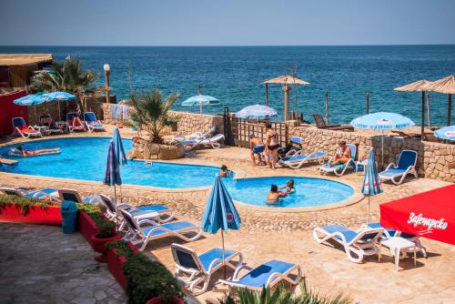 a swimming pool with chairs and umbrellas and the ocean at David Lux beach rooms in Dobra Voda