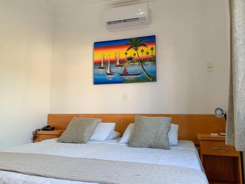 a bedroom with a bed and a painting on the wall at Pousada Vale Del Sol in Bombinhas