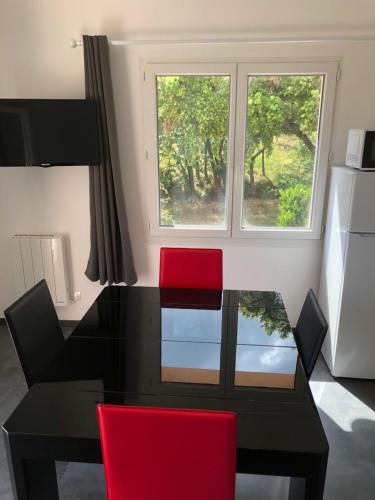 a dining room table with two red chairs and a window at L'Oliveraie in La Londe-les-Maures
