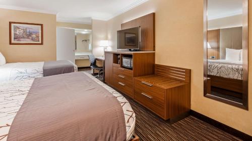 a hotel room with two beds and a flat screen tv at Best Western Airpark Hotel - Los Angeles LAX Airport in Inglewood
