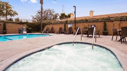 a hot tub with chairs and tables next to a pool at Best Western Airpark Hotel - Los Angeles LAX Airport in Inglewood