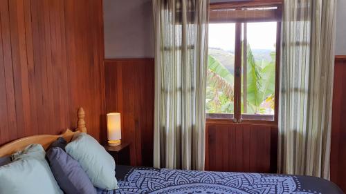 a bedroom with a bed and a window with a view at Montaña Linda Guest House Orosi in Orosí
