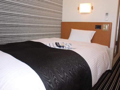 1 dormitorio con 1 cama grande con sábanas blancas en APA Hotel Tokushima Ekimae, en Tokushima