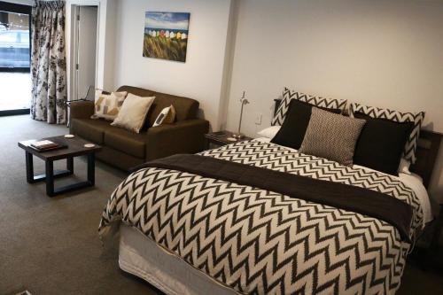 a bedroom with a large bed and a couch at STUDIO@746 in Queenstown
