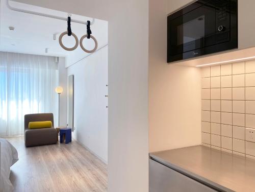 a room with a kitchen with a tv and a chair at Stey Beijing 798 Art Zone Hotel in Beijing